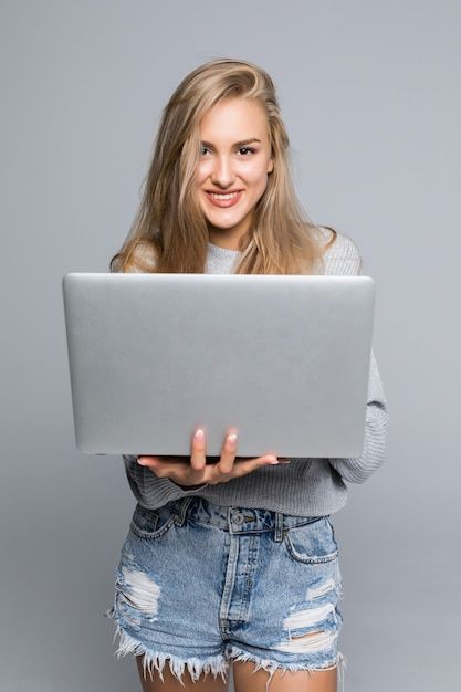 Free Photo _ Young happy smiling woman in casual clothes holding laptop and sending email to her best friend isolated on gray background